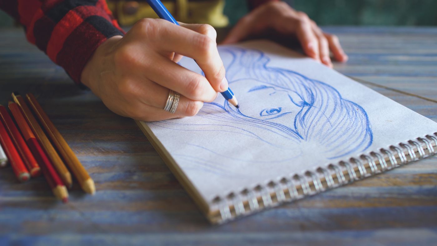 Close-up of a blue-pencil portrait drawing in a sketchbook