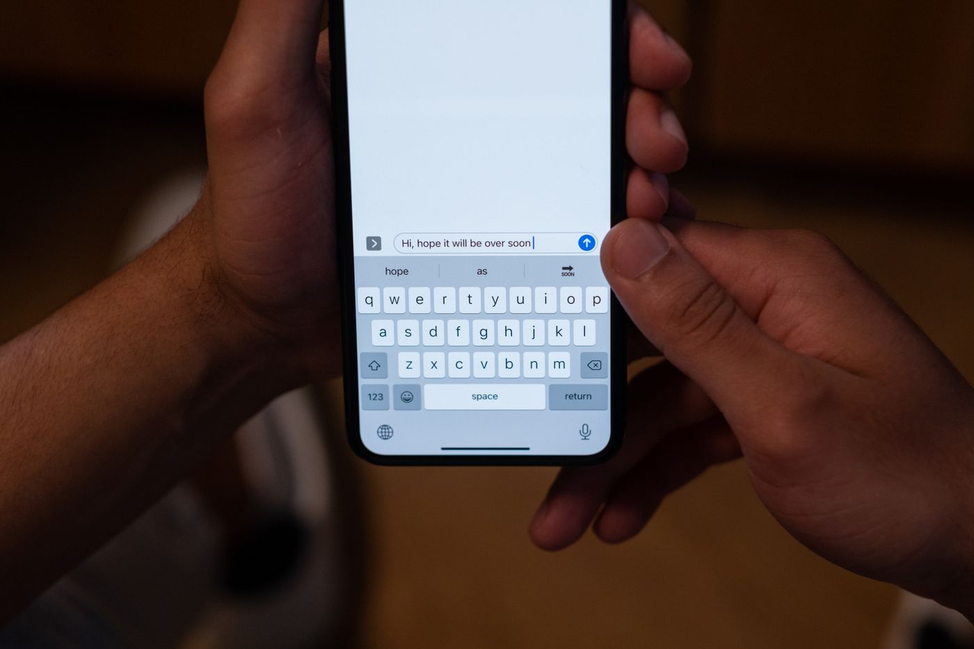 Hands using a smartphone to send a message